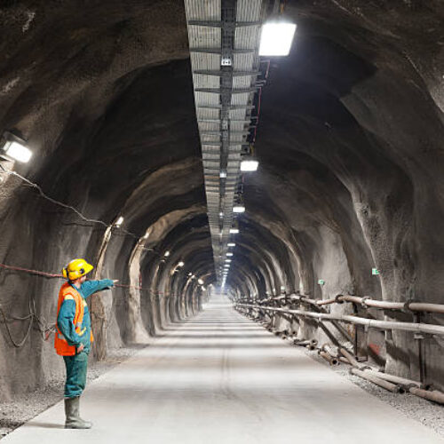 Professional underground workerpointing downward in a tunnel/mine.