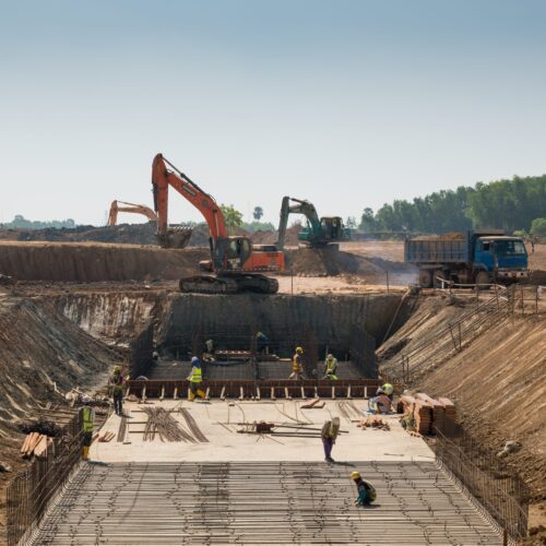 A close shot of heavy machines and construction workers working on a building